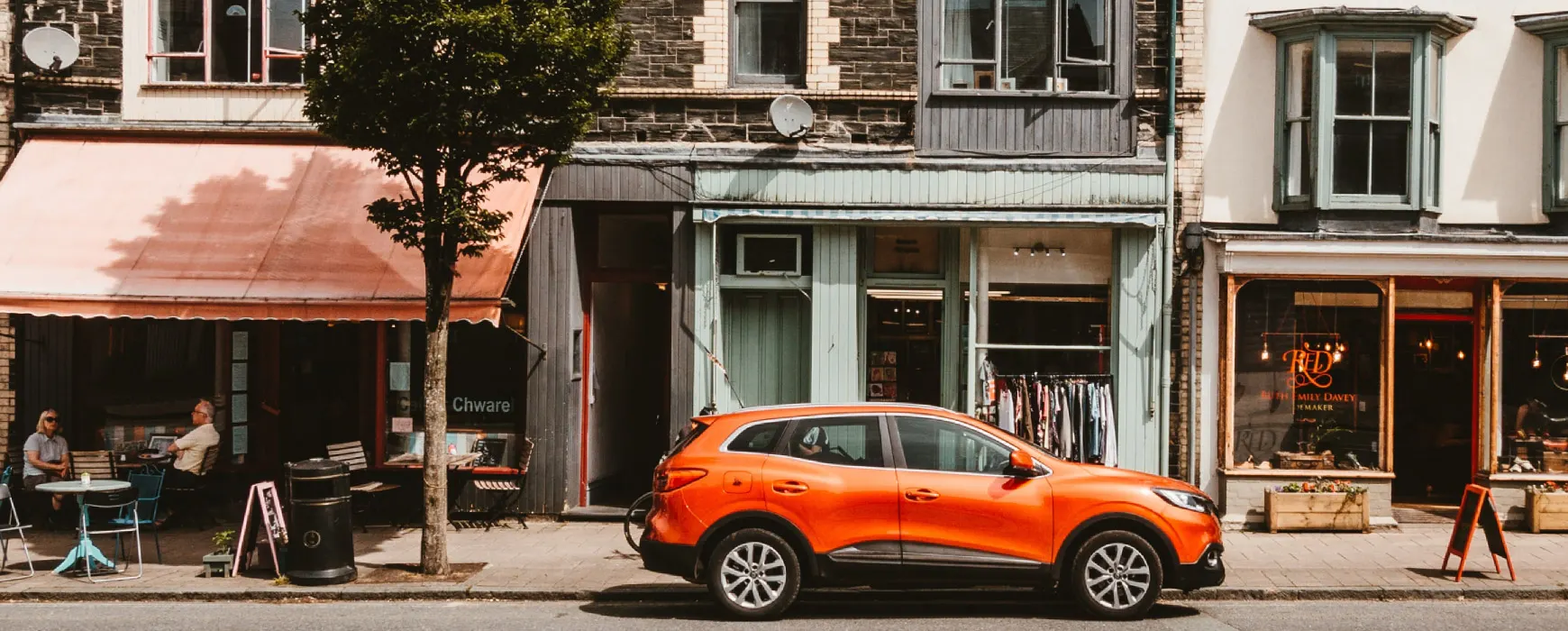A orange SUV in front of houses on a street